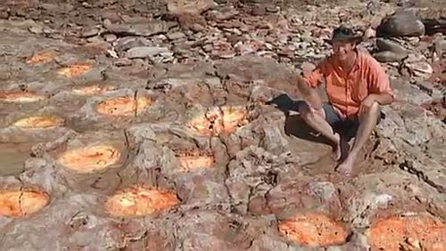 Host Mark Horstman pointing to dinosaur tracks (highlighted)